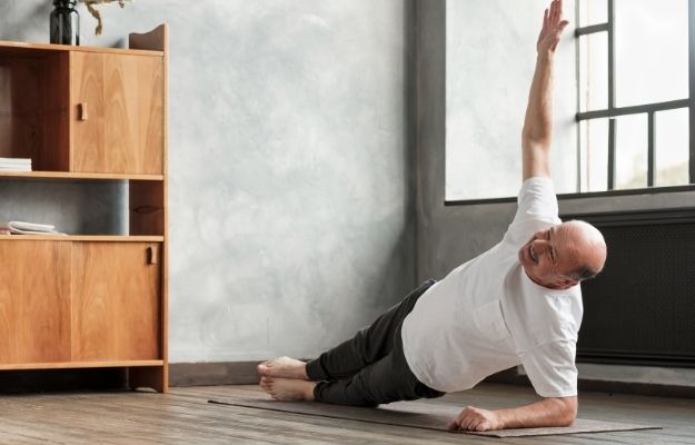 Cheerful senior hispanic man doing a side plank exercise at living room | Keep Moving | Maintain Your Physical Vitality with These 5 Life Hacks