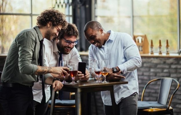 group of man grabbing a drink and laughing together after work-ca