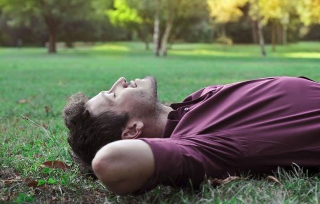 man lying on grass and practicing mindfulness | The Benefits of Meditation | When Is The Best Time To Meditate For Optimized Health?
