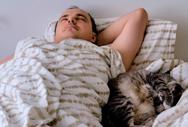 middle-aged-man-sleeping-in-with-cat