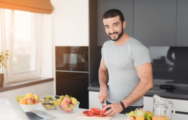 happy man is sliding tomatoes in kitchen | The Bottom Line | Benefits of Fenugreek for Testosterone