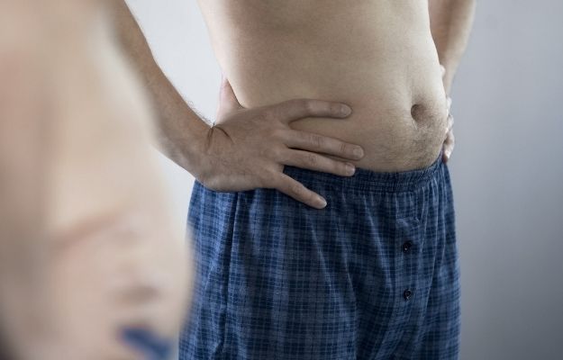 Aged man looking at his belly in the mirror | Common ED Causes, Symptoms, and Treatments