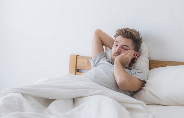man feeling tired and misaligned sleeping pattern because of sleeping in | Is Sleeping In Bad For Your Sleep Routine or Health