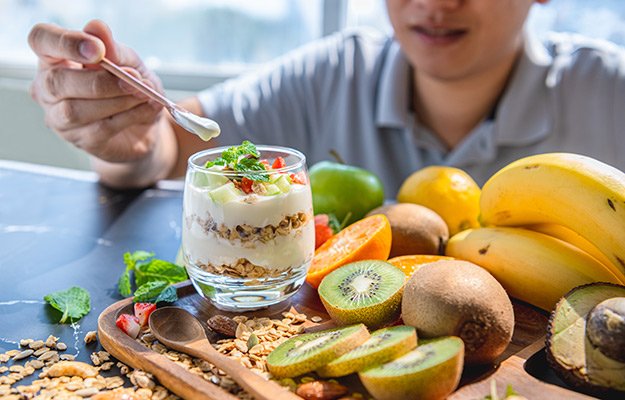 A man eating yogurt with kiwi, banana, grain, strawberry | How to Improve Gut Microbiome