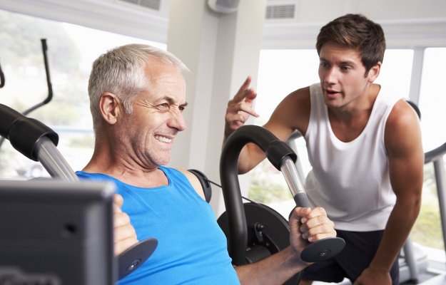 A middle age man with his Personal Trainer In Gym | What Is a Hypertrophy Workout?