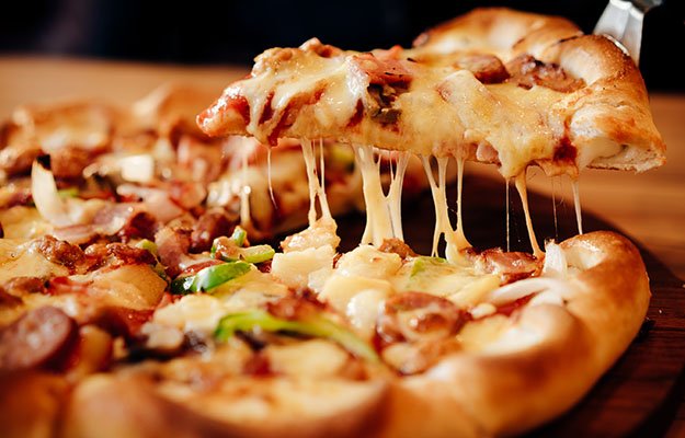 slice of pizza on wooden board-too much comfort food | 10 Deadly Disruptors to Your Gut Microbiome