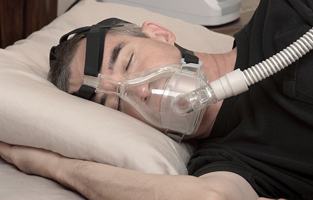 A man having sleep apnea and wearing breathing machine | What Causes Sleep Apnea and How to Prevent It