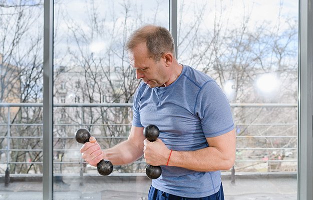 A middle aged man lifting light weight | What Causes Osteoporosis in Men and Who Is Vulnerable to This Bone Disease?