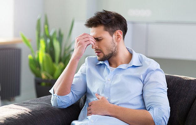 Man On Sofa Having Headache and stomach-ache-stress and sleep health | 10 Deadly Disruptors to Your Gut Microbiome