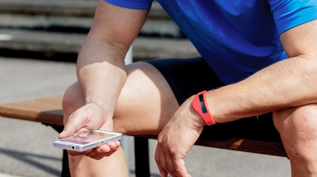 Man checking performance on mobile ai tracking while resting after workout