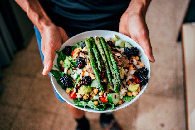 Man holding tasty vegan bowl with asparagus