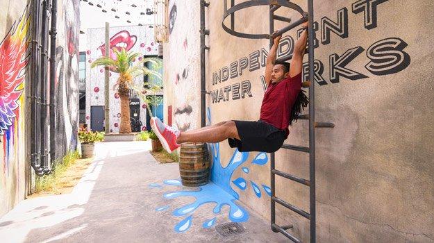 man with dreadlocks does pullups on stairs on the street