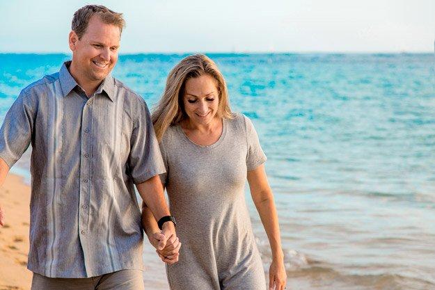 Middle aged couple walking on beach while holding hands intimacy
