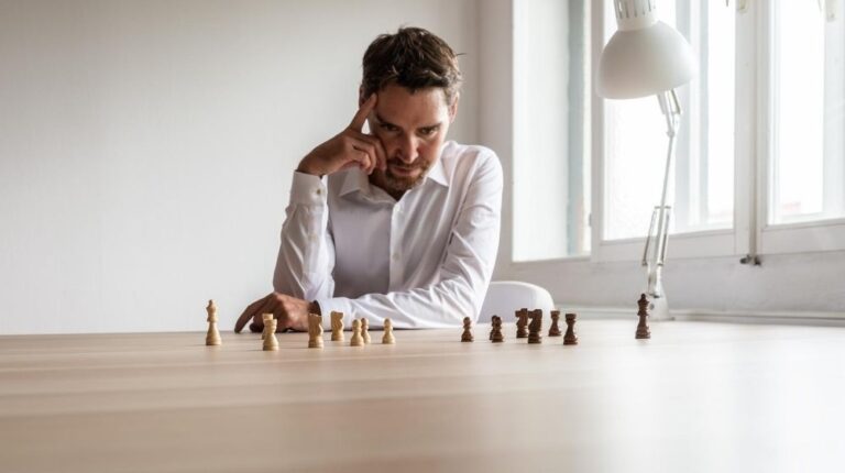 a man playing chess and try to make decision with a lamp next to chesses | feature | How To Strengthen Your Decisiveness Ability