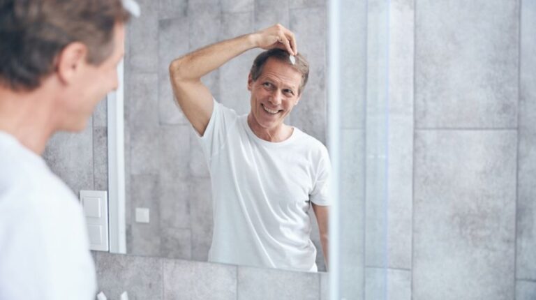 middle-aged man is combing his hair in front of mirror | Feature | 7 Tips & Tricks To Deal With Receding Hairline In Men