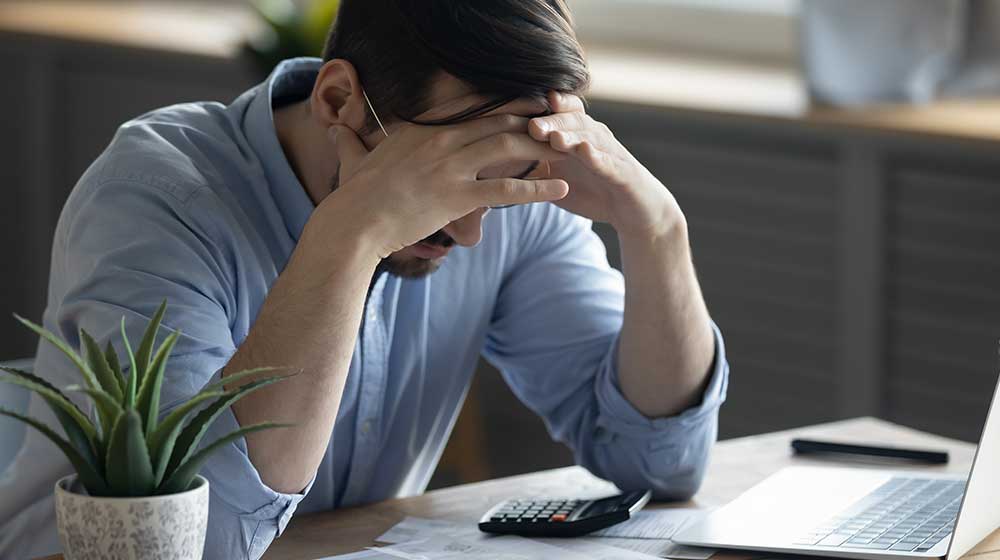 Distressed-young-Caucasian-man-sit-at-desk | feature | What's the Connection Between Stress and Weight Gain?