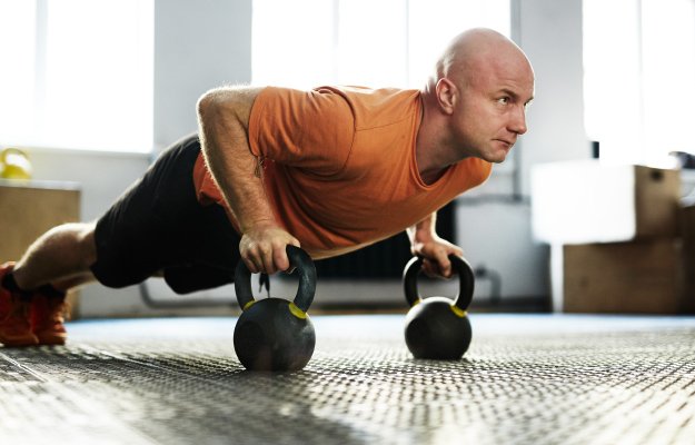 bald-middle-aged-sportsman-standing-in-plank-position-with-help-of-kettlebells-----------ENERGY-AND-FOCUS-----------_body | The Benefits of Strength Training in Your 40’s and 50’s | ENERGY-AND-FOCUS